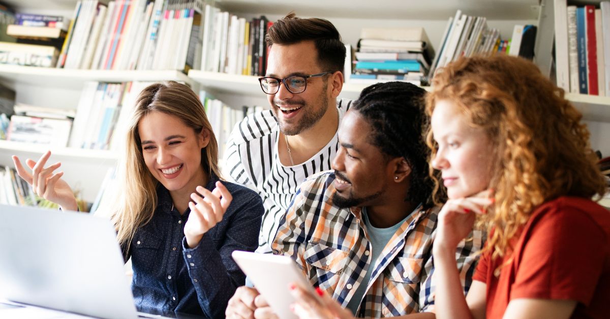 A team looking at one computer and smiling