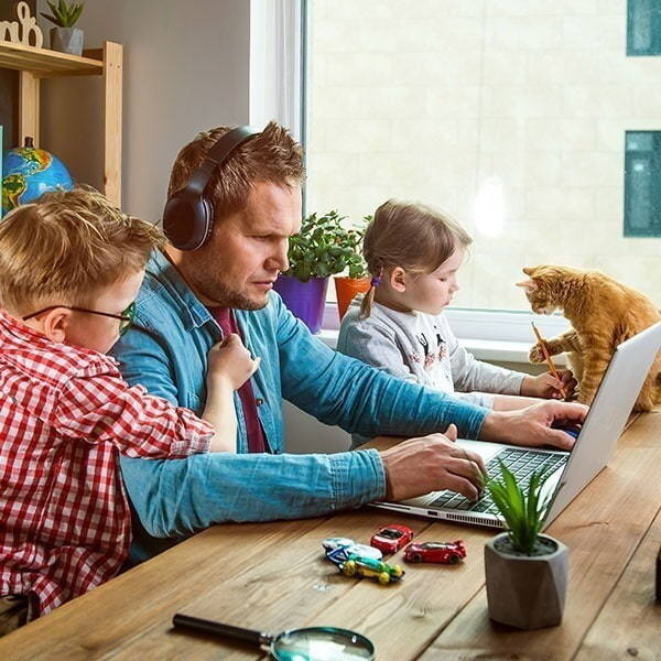 Person working at home at the same table as their children