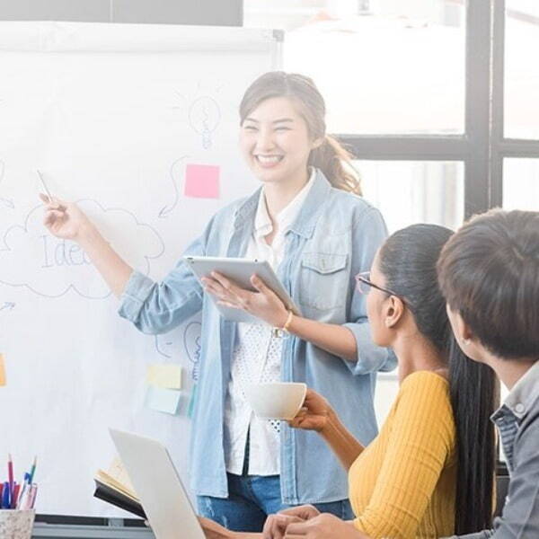 Smiling person presenting to their team by a whiteboard